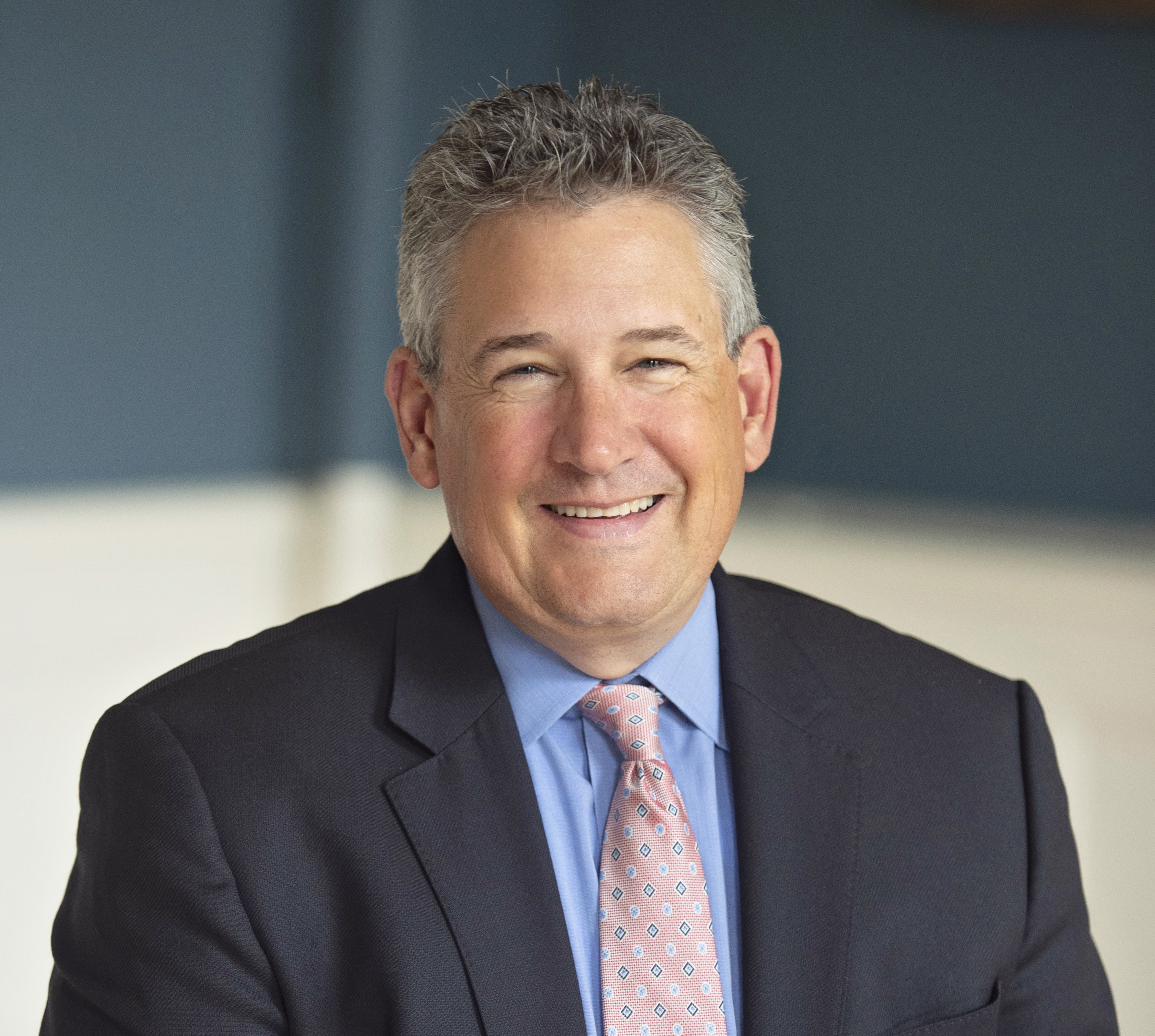 A man in suit and tie smiling for the camera.